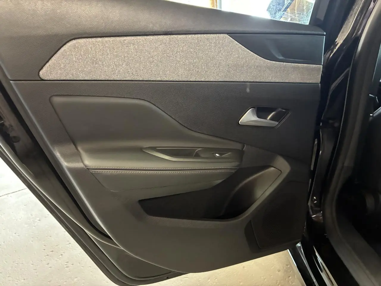 Vue intérieure côté gauche de la porte arrière noire du Peugeot 308 SW 2024 avec habillage tissu et plastique.
