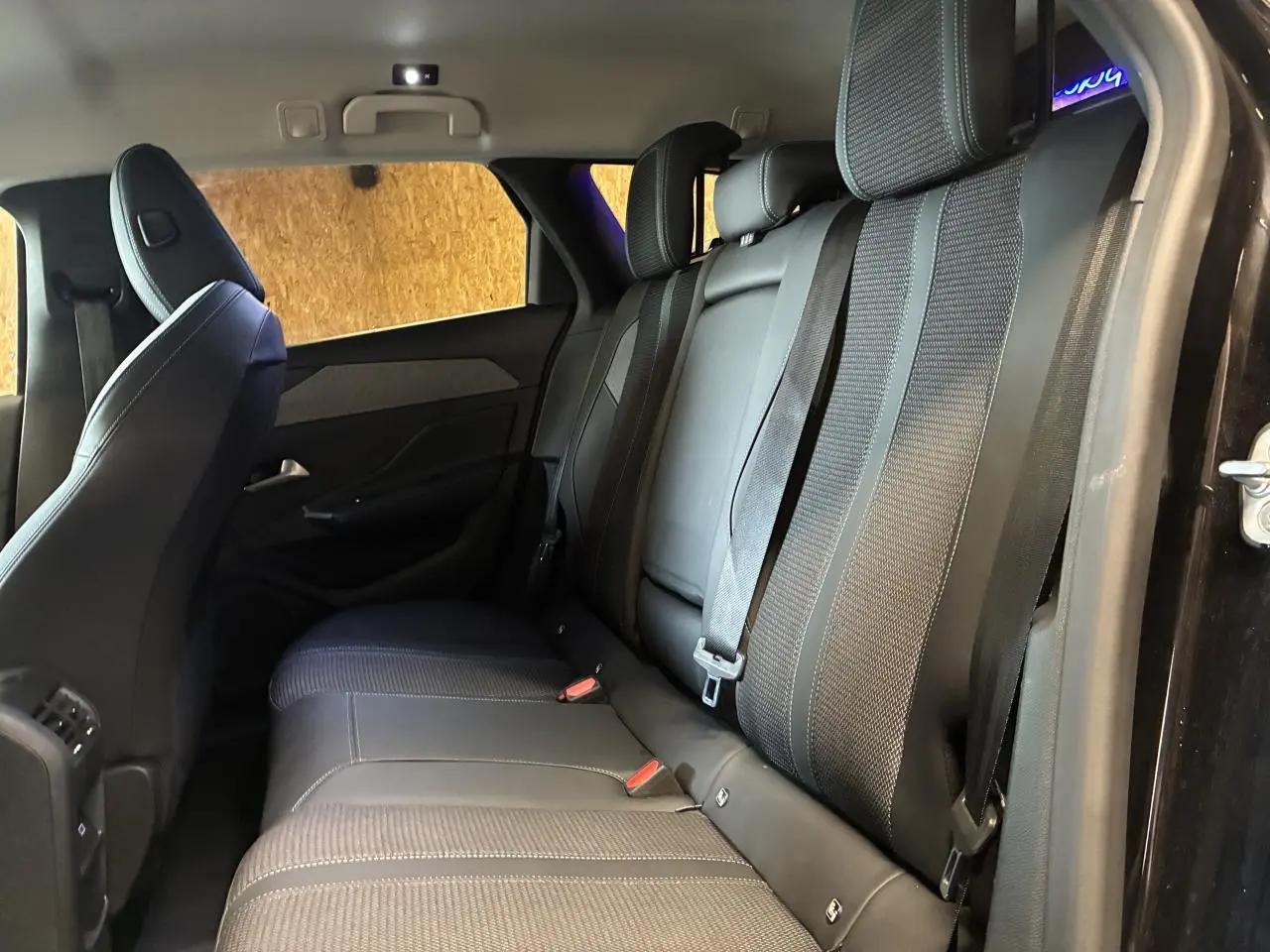 Vue latérale intérieure montrant la banquette arrière noire avec ceintures et surpiqûres sur un Peugeot 308 SW 2024.