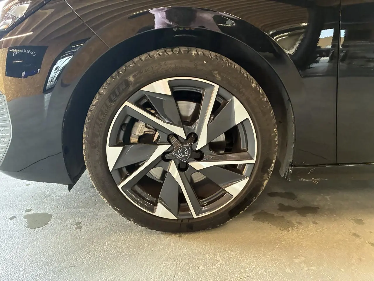 Gros plan sur la roue avant gauche noire d'une Peugeot 308 SW 2024 avec jante alliage 17'' Halong diamantée.