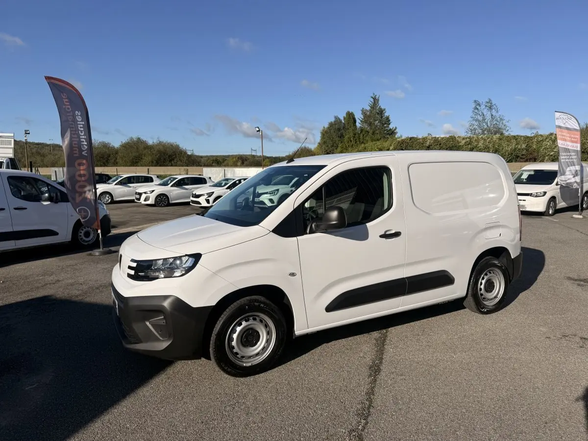 Peugeot Partner blanc en vue 3/4 avant droit, avec protections noires latérales et jantes acier simples.