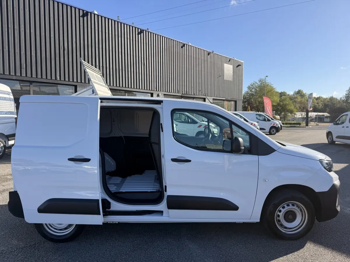 Vue latérale droite d’un Peugeot Partner blanc 2026 avec porte coulissante ouverte montrant l’espace de chargement.