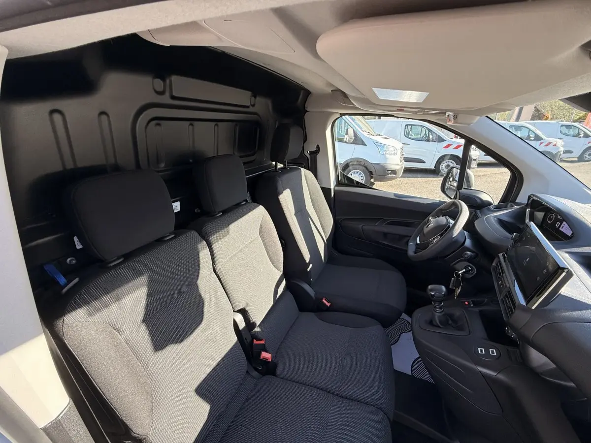 Intérieur avant du Peugeot Partner blanc 2026, vue côté droit montrant sièges tissu gris et tableau de bord moderne.