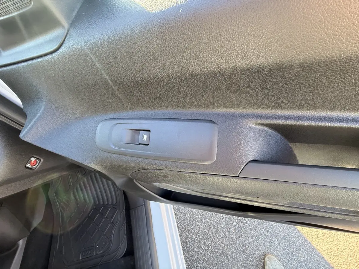 Vue intérieure sur la porte côté conducteur du Peugeot Partner blanc, avec commande de vitre électrique visible.