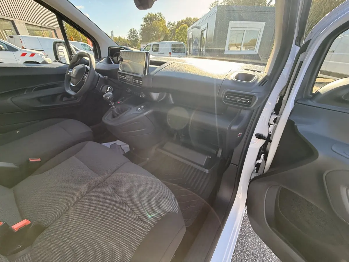 Vue intérieure côté passager du Peugeot Partner blanc 2026, montrant sièges, tableau de bord et volant multifonctions.