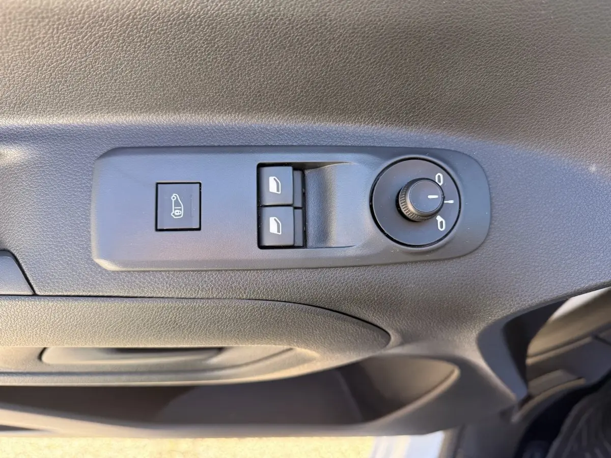 Détail des commandes de réglage des rétroviseurs et des vitres sur la porte côté conducteur d’un Peugeot Partner blanc.