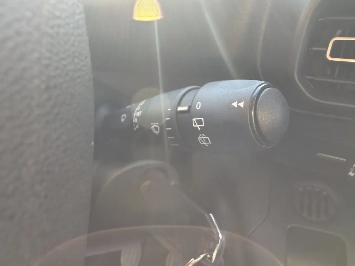 Gros plan sur la commande d’essuie-glace à gauche du volant dans l’habitacle du Peugeot Partner blanc.