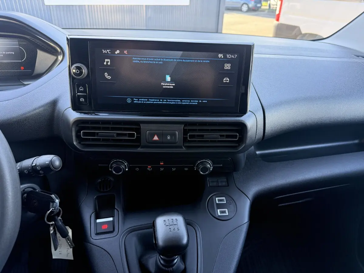 Vue intérieure du tableau de bord du Peugeot Partner blanc 2026, avec écran tactile central et levier de vitesses manuel.