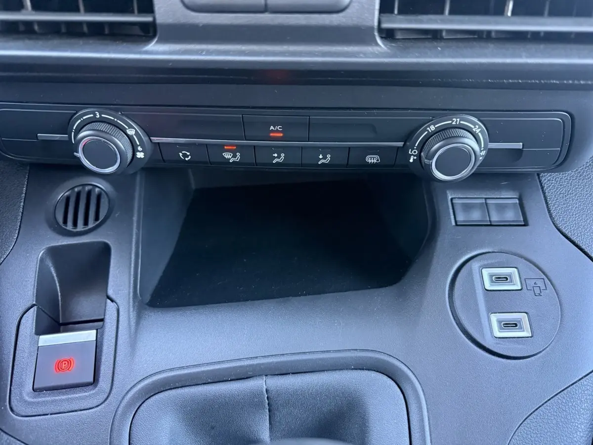 Vue rapprochée de la console centrale noire du Peugeot Partner 2026 avec commandes climatisation et ports USB visibles.
