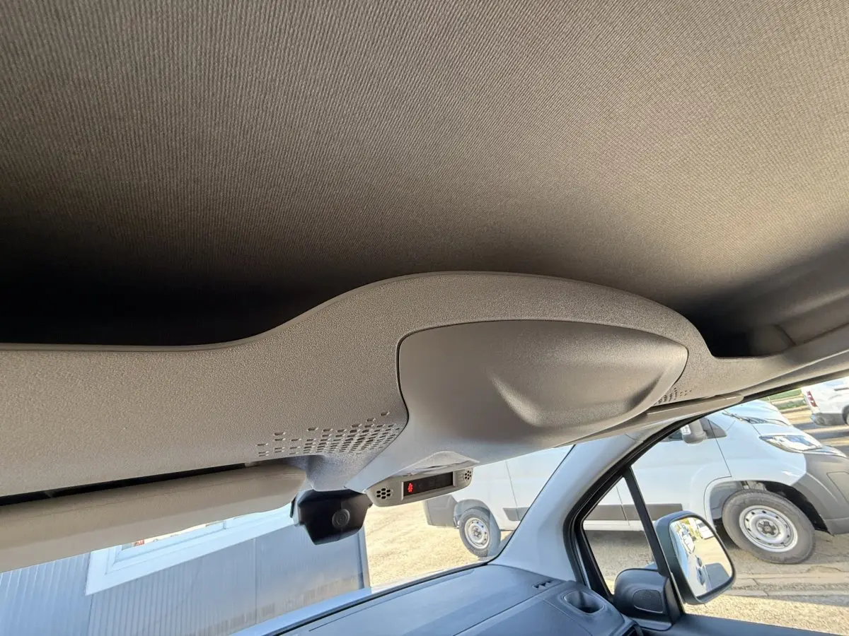 Vue intérieure du plafond et pare-soleil côté conducteur du Peugeot Partner blanc, avec rétroviseur et partie du tableau de bord visibles.