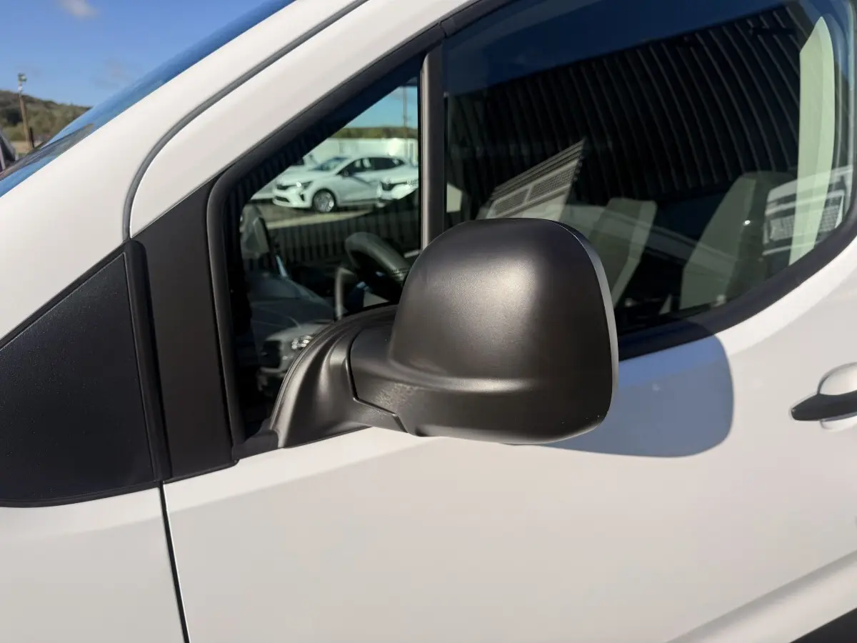 Rétroviseur noir côté conducteur du Peugeot Partner blanc, vue rapprochée sur la porte avant gauche.