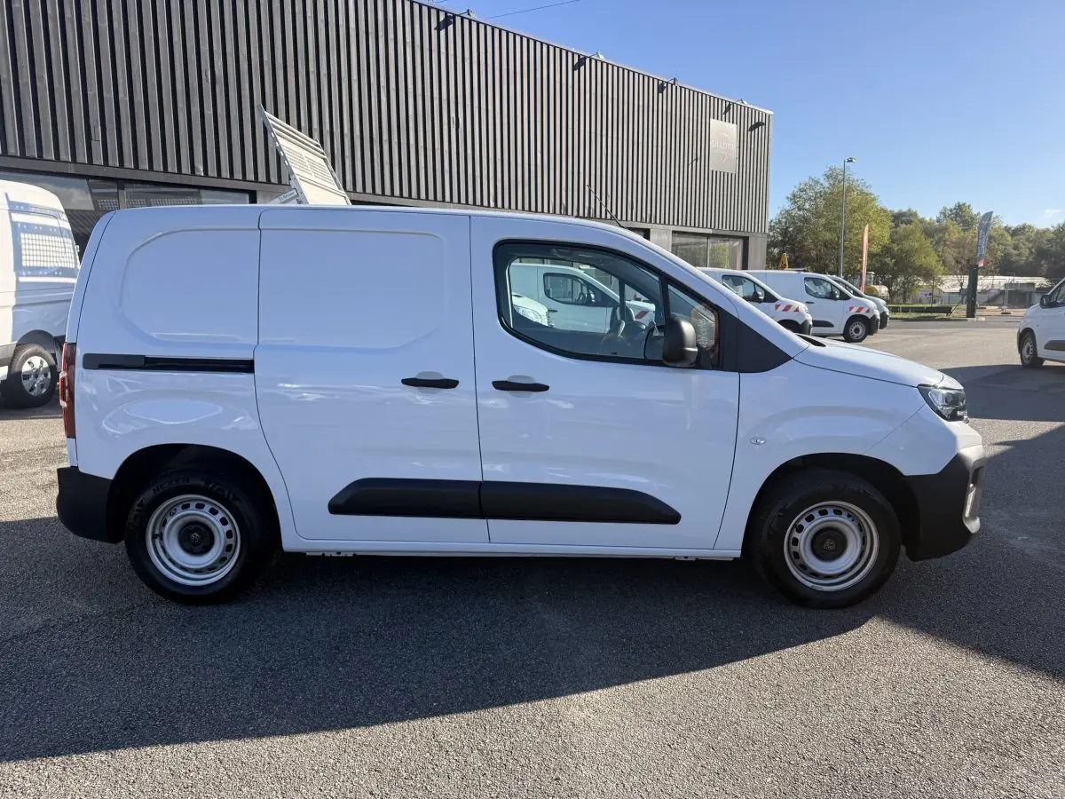 Vue de profil côté gauche d’un utilitaire Peugeot Partner blanc avec protections noires sur porte et roues acier.