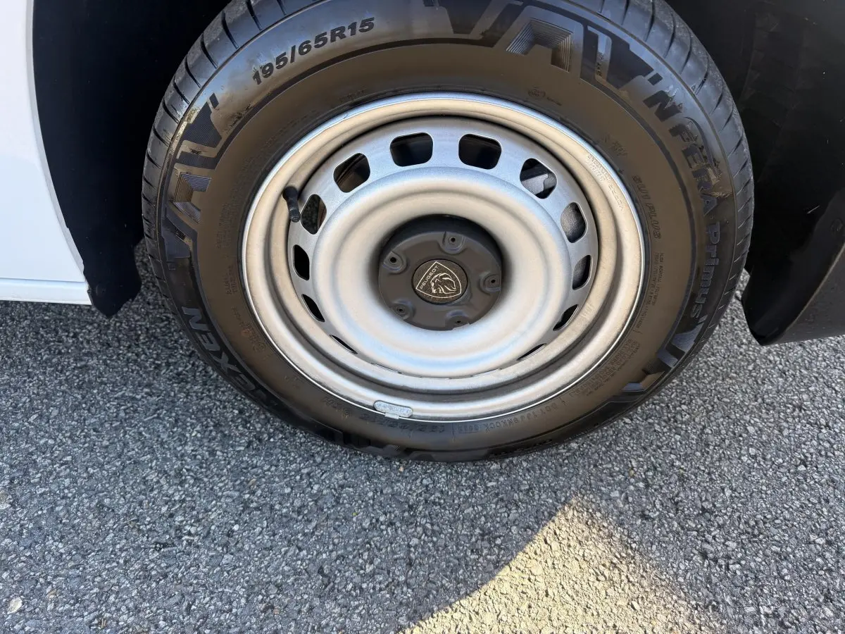 Gros plan sur la roue avant gauche du Peugeot Partner blanc, mettant en valeur la jante acier et le pneu Nexen.