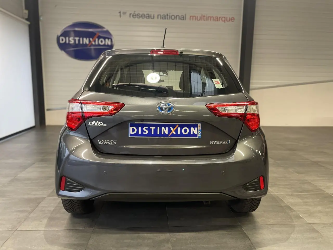 Vue arrière d'une Toyota Yaris hybride gris foncé métallisé avec feux arrière nets et logo distinctif.