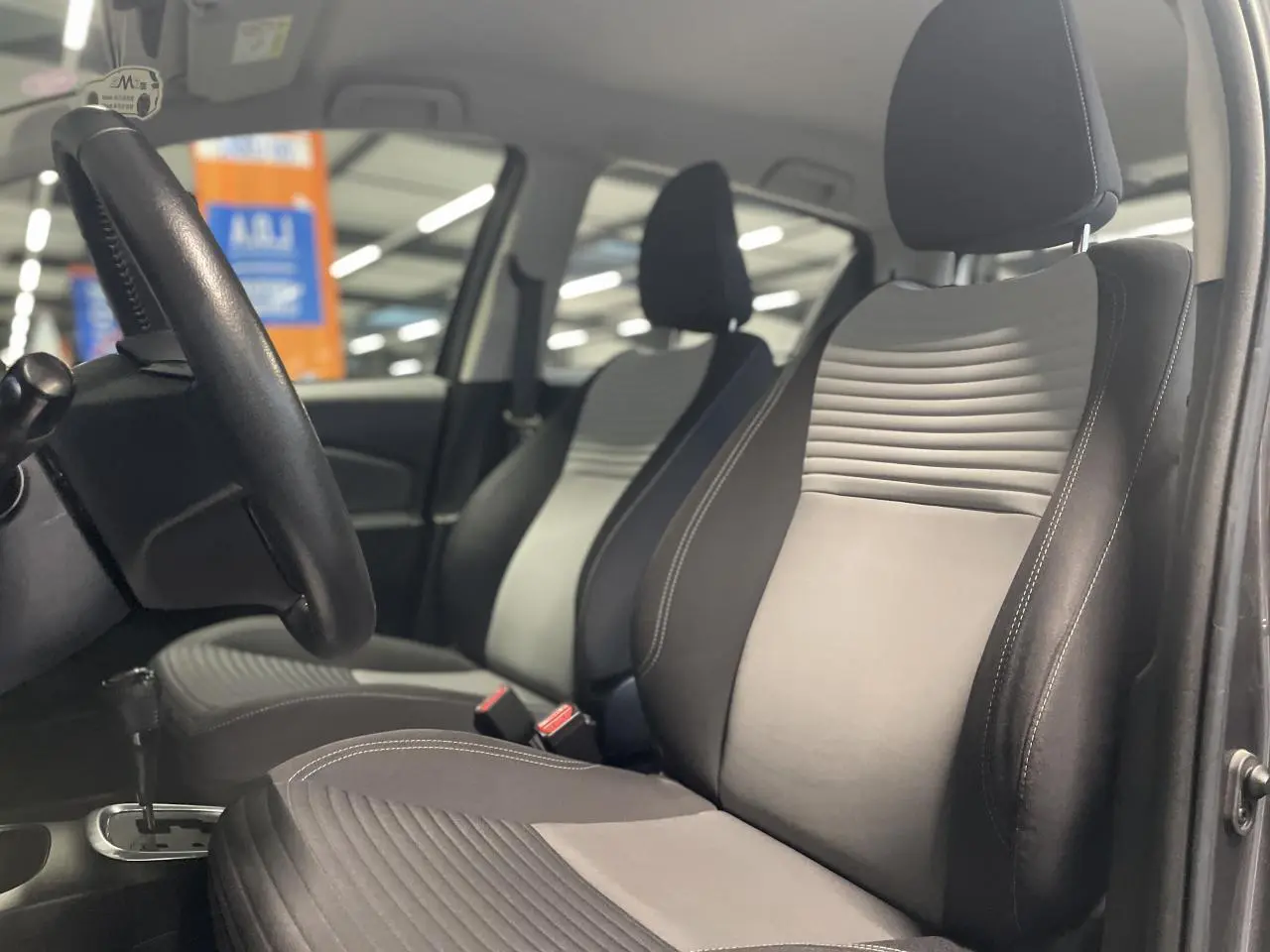 Vue intérieure côté conducteur de la Toyota Yaris hybride 2020, sièges tissu gris clair et foncé, volant cuir noir.