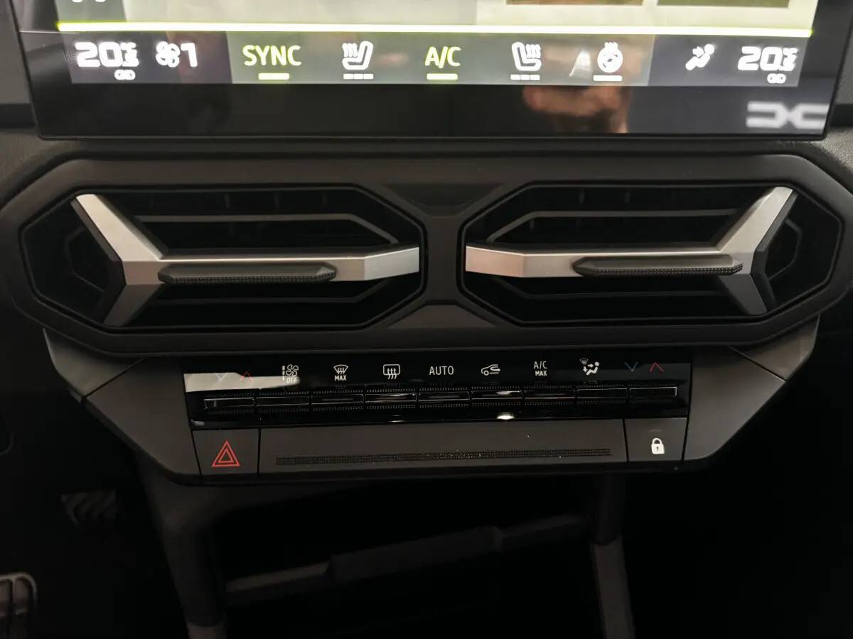 Détail du tableau de bord central du Dacia Bigster 2025 gris foncé, avec commandes climatisation et aérateurs hexagonaux.