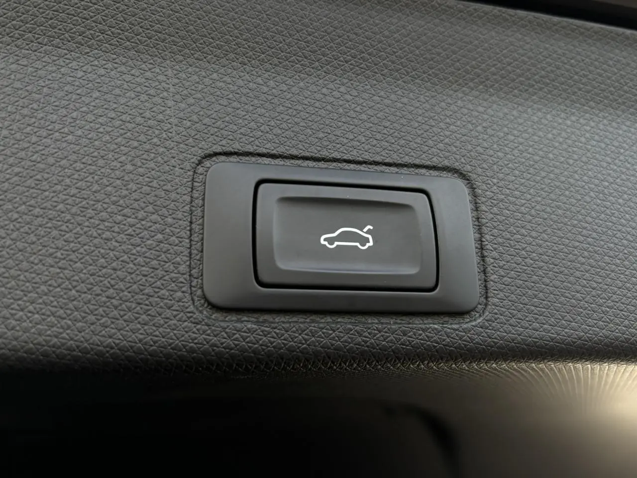 Bouton noir d'ouverture électrique du hayon sur panneau intérieur texturé du coffre du CUPRA TERRAMAR Dark Void.
