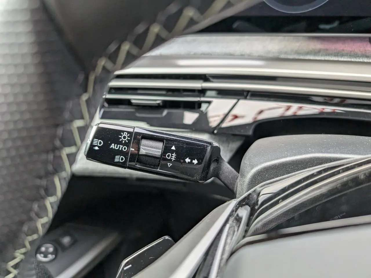 Gros plan sur la commande des feux et clignotants côté gauche du Peugeot 3008 GT 2025 bleu métallisé.