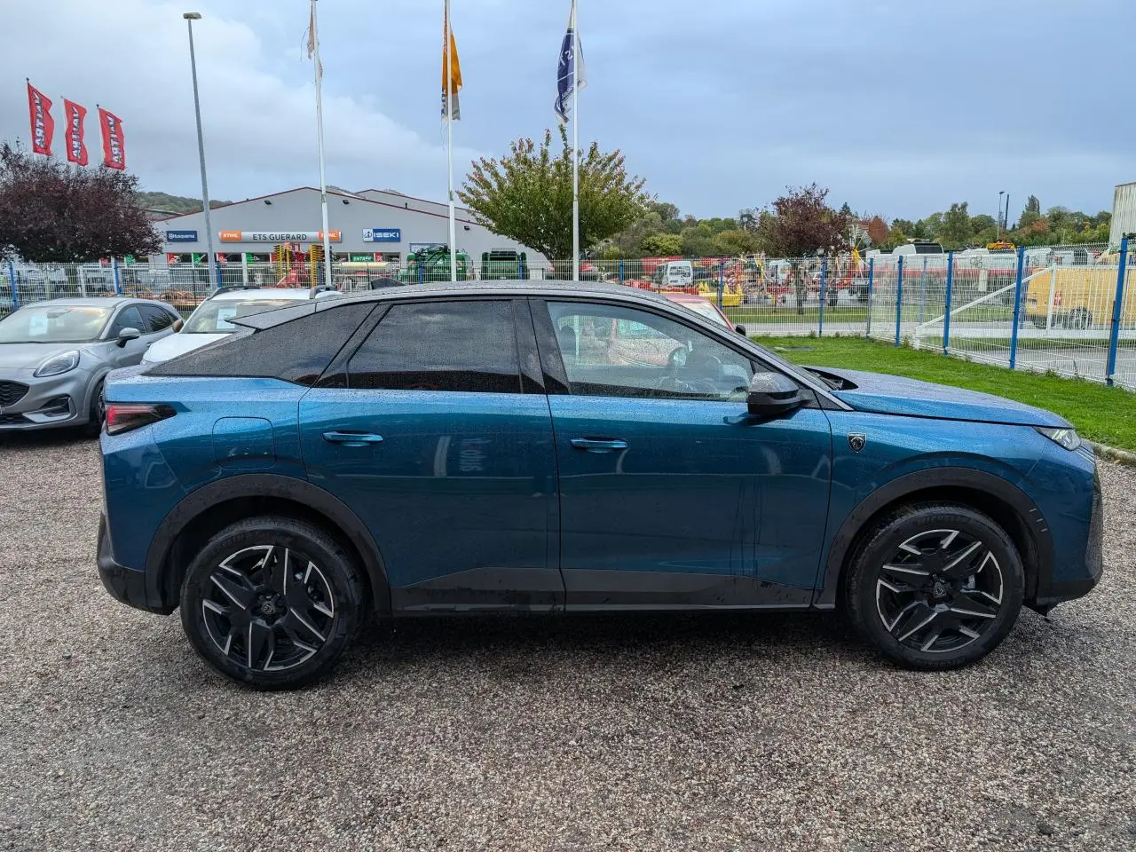 Peugeot 3008 GT hybride bleu métallisé, vue de profil côté gauche, jantes alliage noires et toit noir contrasté.