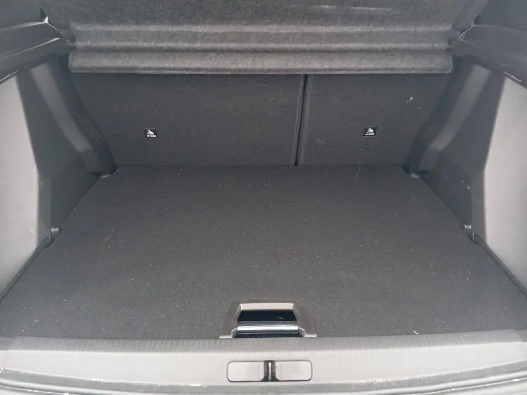Coffre vide en vue arrière du Peugeot 2008 Hybrid blanc, montrant l'espace de chargement et la moquette noire.