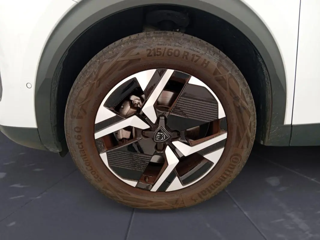 Gros plan sur la roue avant droite du Peugeot 2008 blanc, jante alliage 17 pouces au design moderne bicolore.