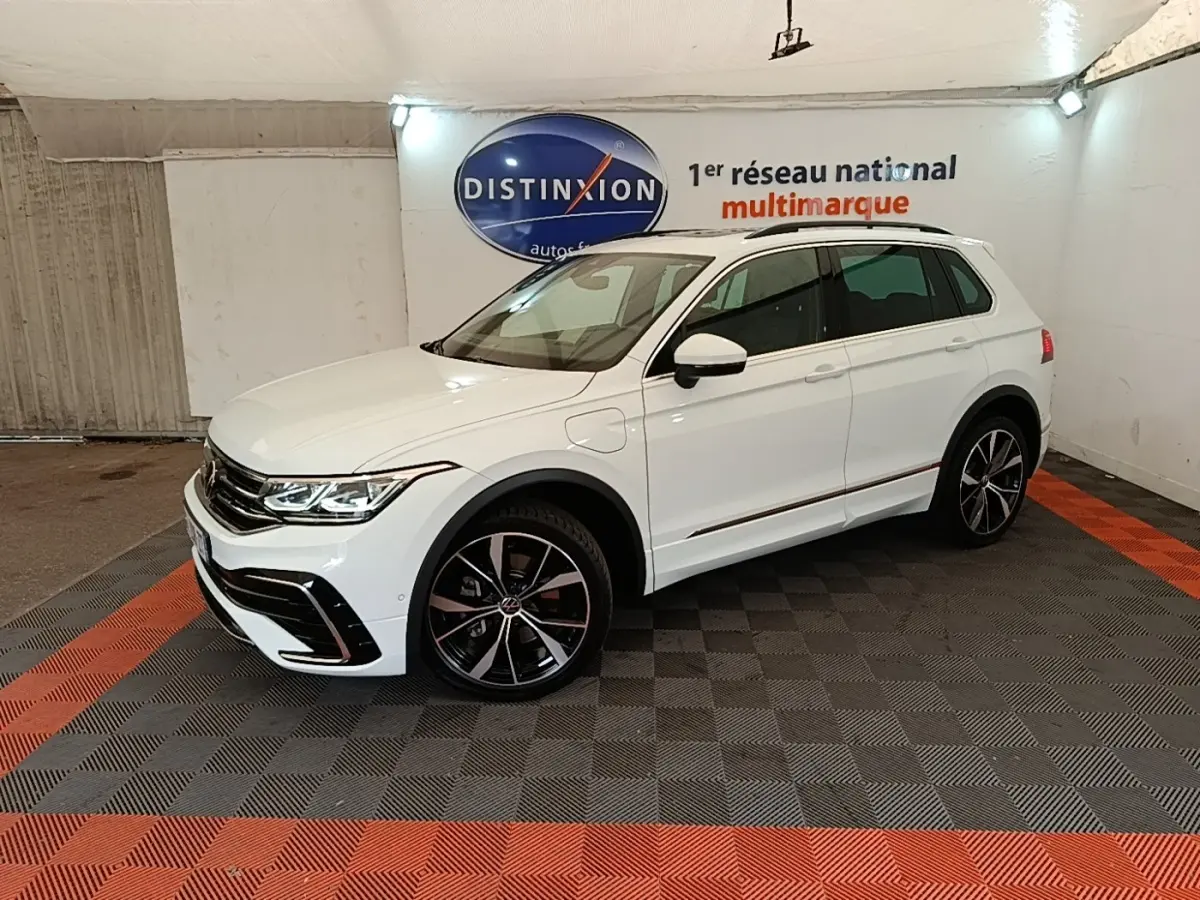 Volkswagen Tiguan 1.4 eHybrid blanc en 3/4 avant droit, avec jantes noires et détails R-Line visibles.