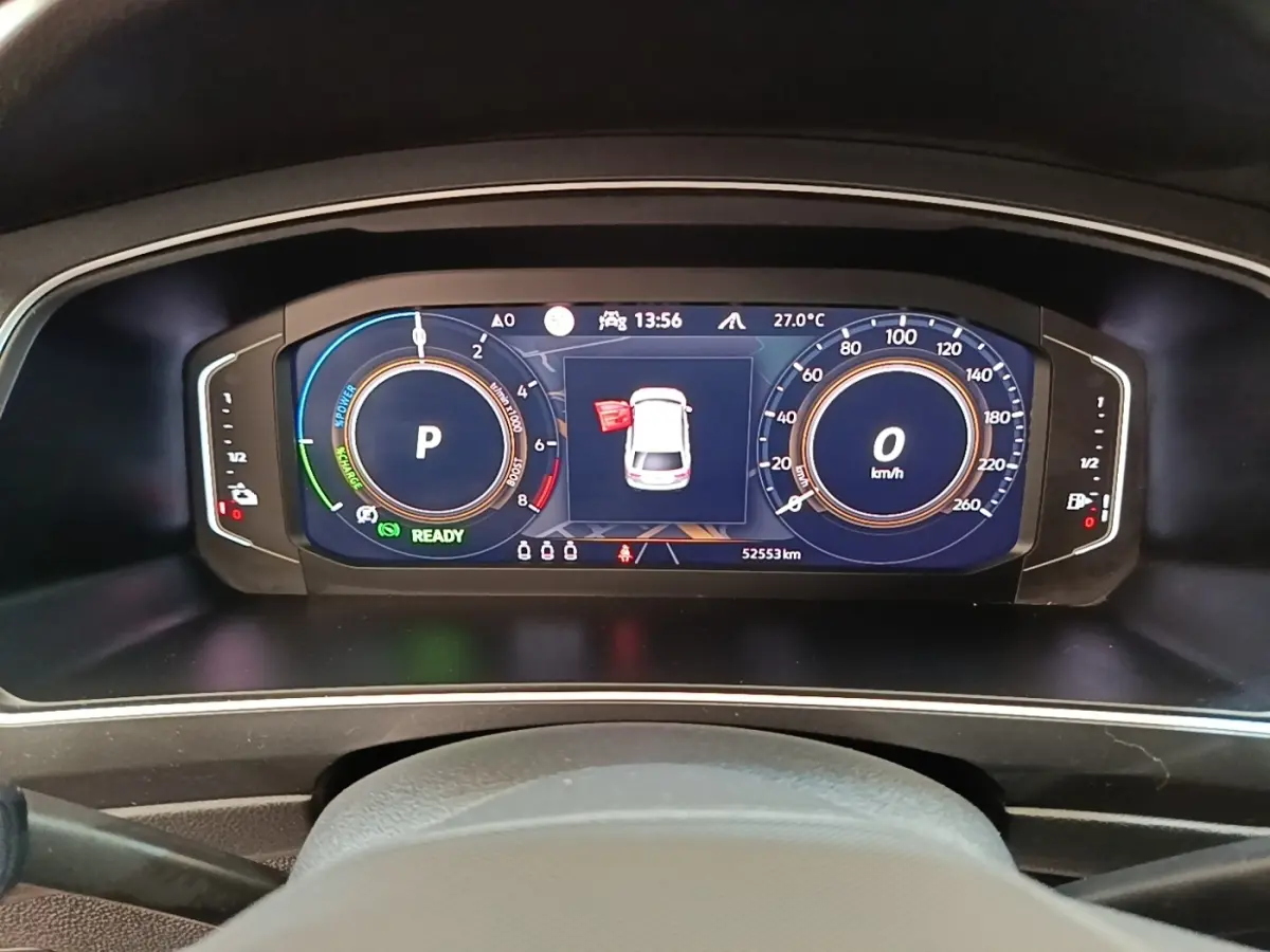 Vue rapprochée du tableau de bord numérique du Volkswagen Tiguan blanc, affichant vitesse, régime et alertes.
