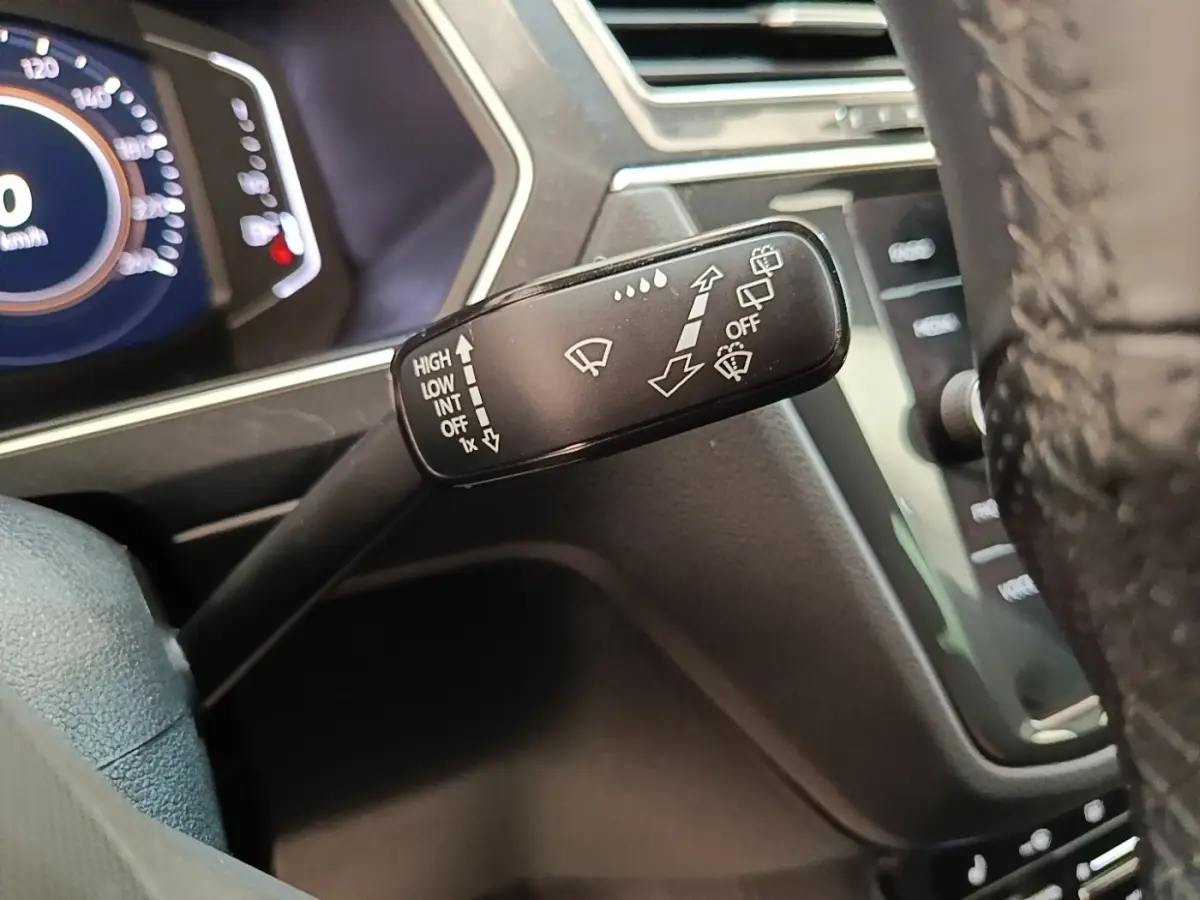 Gros plan sur la commande des essuie-glaces du Volkswagen Tiguan 1.4 eHybrid 2023, intérieur noir et tableau de bord digital.