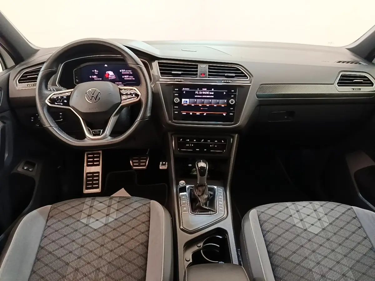 Vue intérieure avant du Volkswagen Tiguan 1.4 eHybrid 2023, tableau de bord noir avec écran tactile central et volant multifonctions.