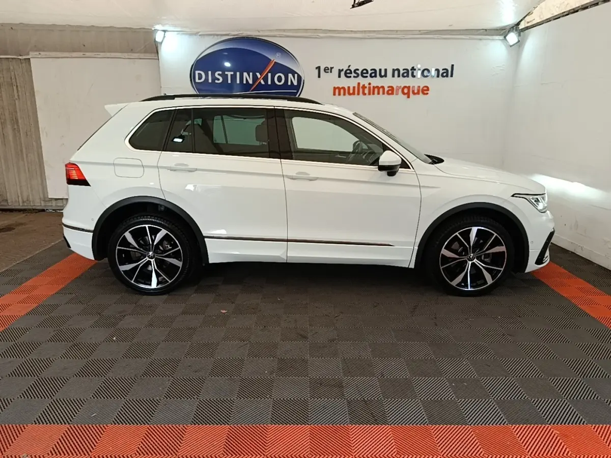 Vue latérale droite d'un Volkswagen Tiguan blanc 1.4 eHybrid 245 DSG6 R-Line dans un showroom intérieur.
