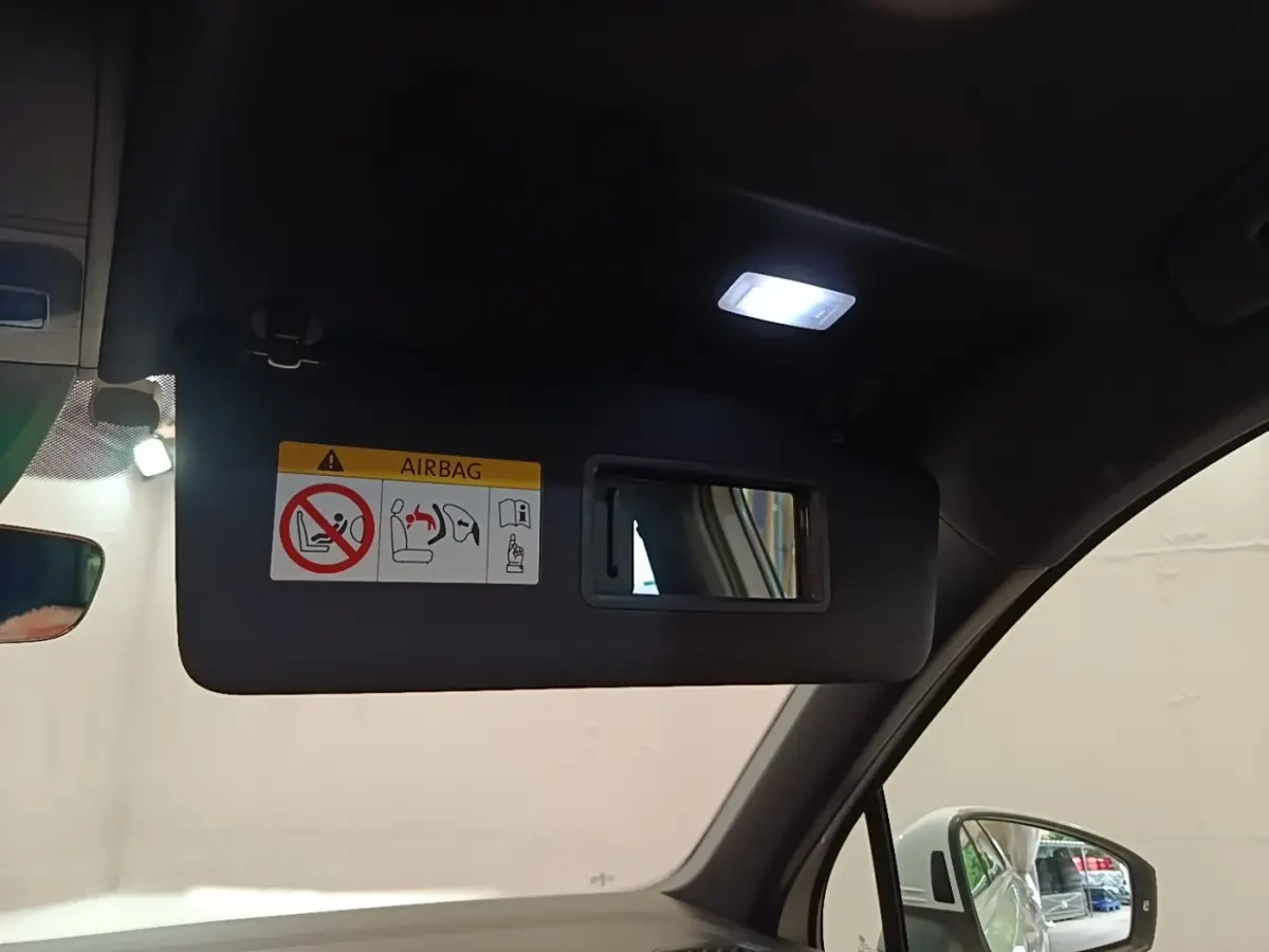 Détail du pare-soleil côté conducteur avec miroir et lumière allumée dans un Volkswagen Tiguan blanc 2023.