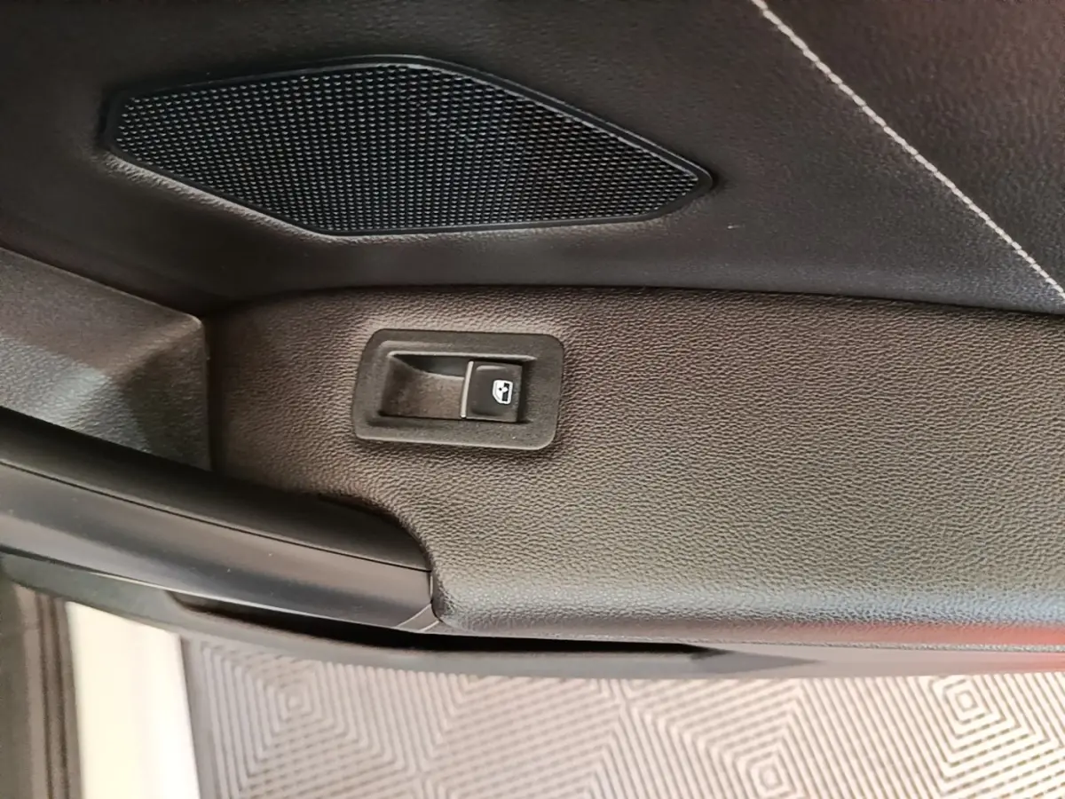Détail du bouton d'ouverture électrique du coffre sur la garniture intérieure noire du Volkswagen Tiguan 1.4 eHybrid 2023.