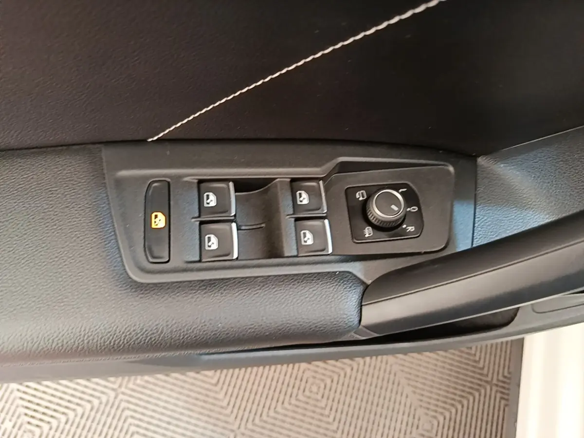 Gros plan sur les commandes des vitres et rétroviseurs côté conducteur du Volkswagen Tiguan blanc 2023.