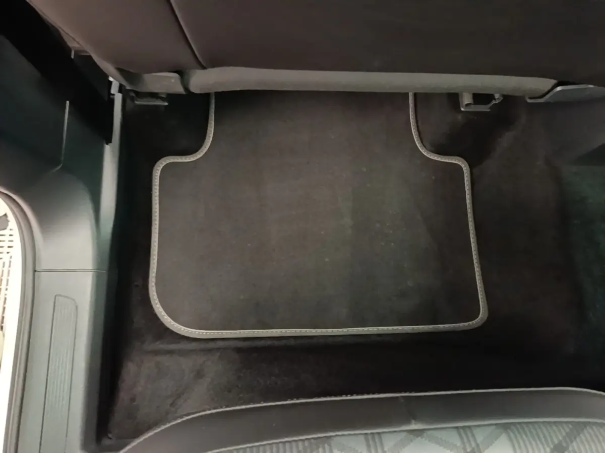 Tapis de sol noir avec surpiqûres grises sous siège arrière d’un Volkswagen Tiguan blanc, vue intérieure au sol.