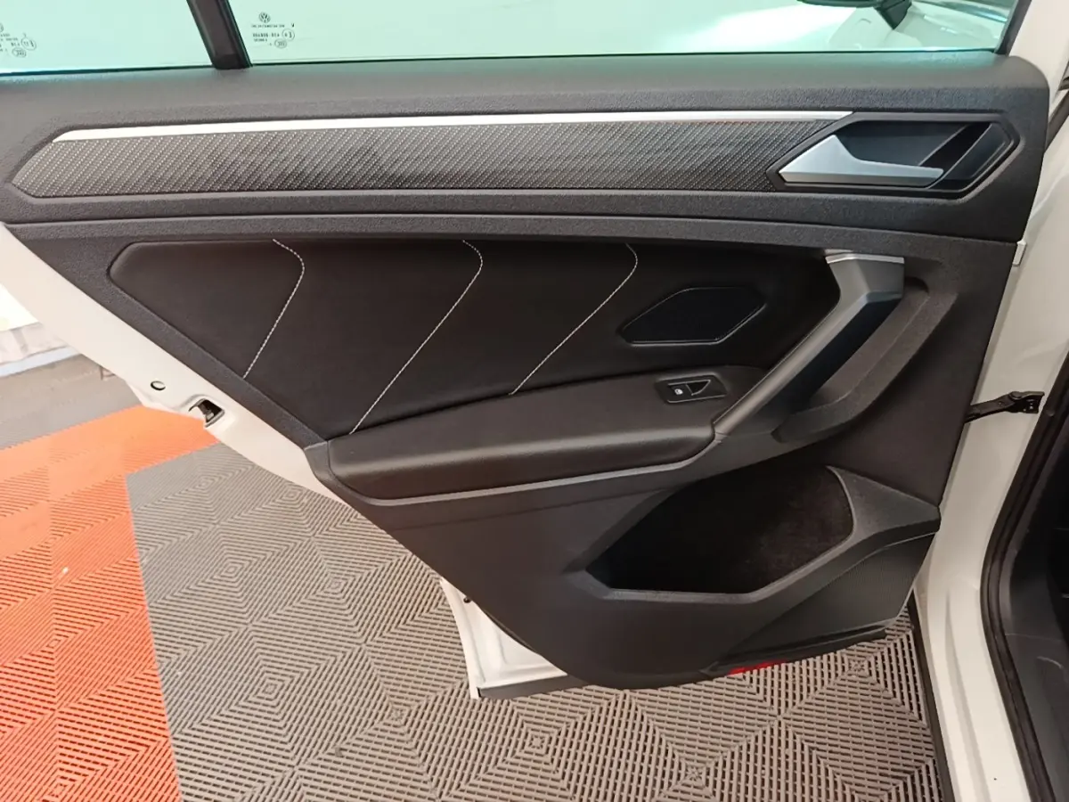 Vue rapprochée de la porte arrière droite blanche du Volkswagen Tiguan 1.4 eHybrid 2023 avec garniture noire et surpiqûres blanches.