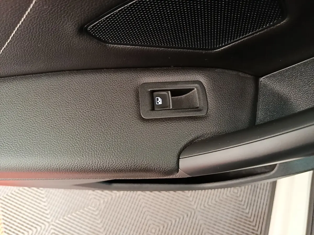 Gros plan sur la commande de verrouillage de porte intérieure noire du Volkswagen Tiguan blanc, côté conducteur.