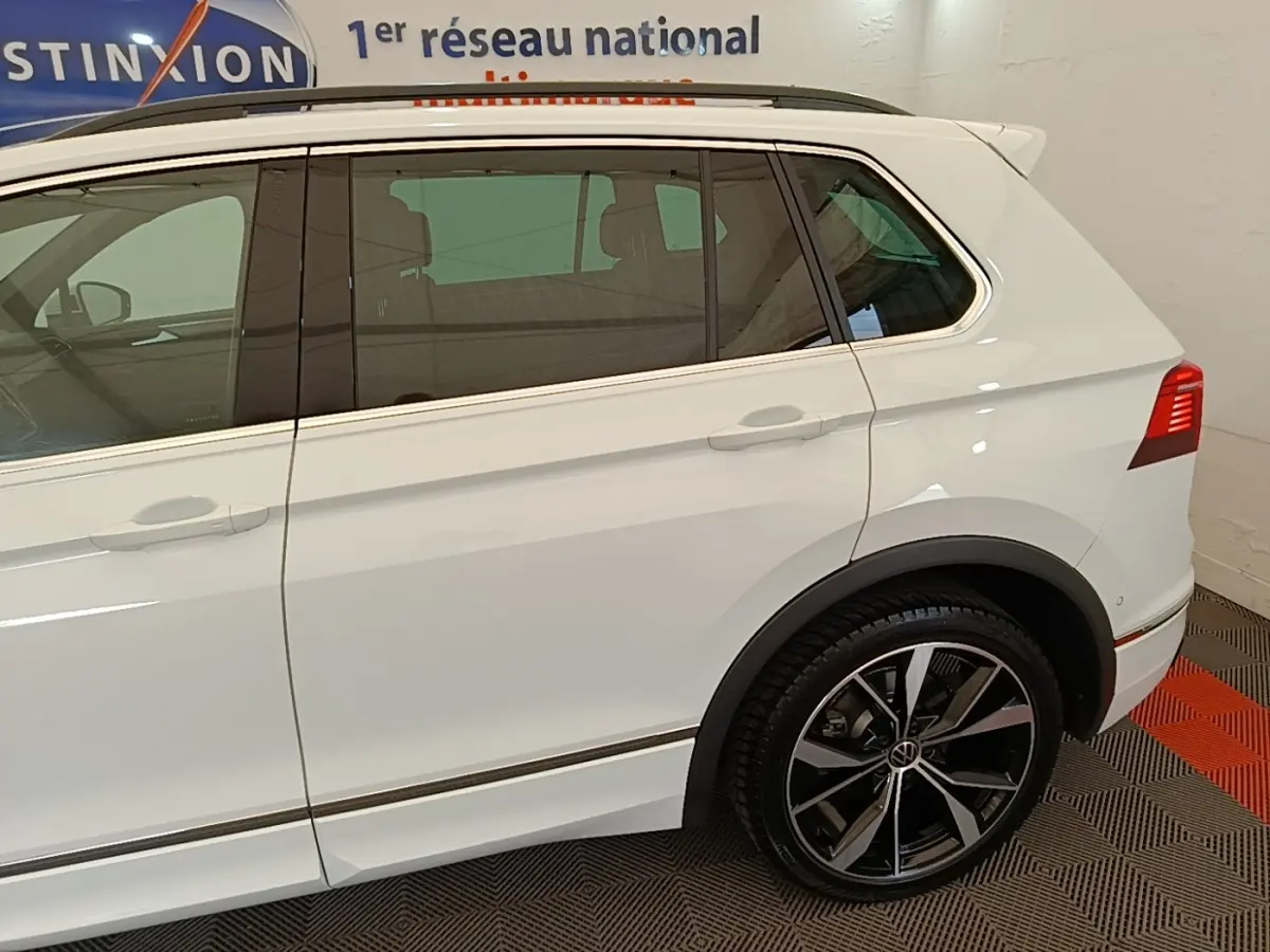 Vue latérale côté gauche d’un Volkswagen Tiguan blanc 1.4 eHybrid 245 DSG6 R-Line avec jantes noires et chrome.