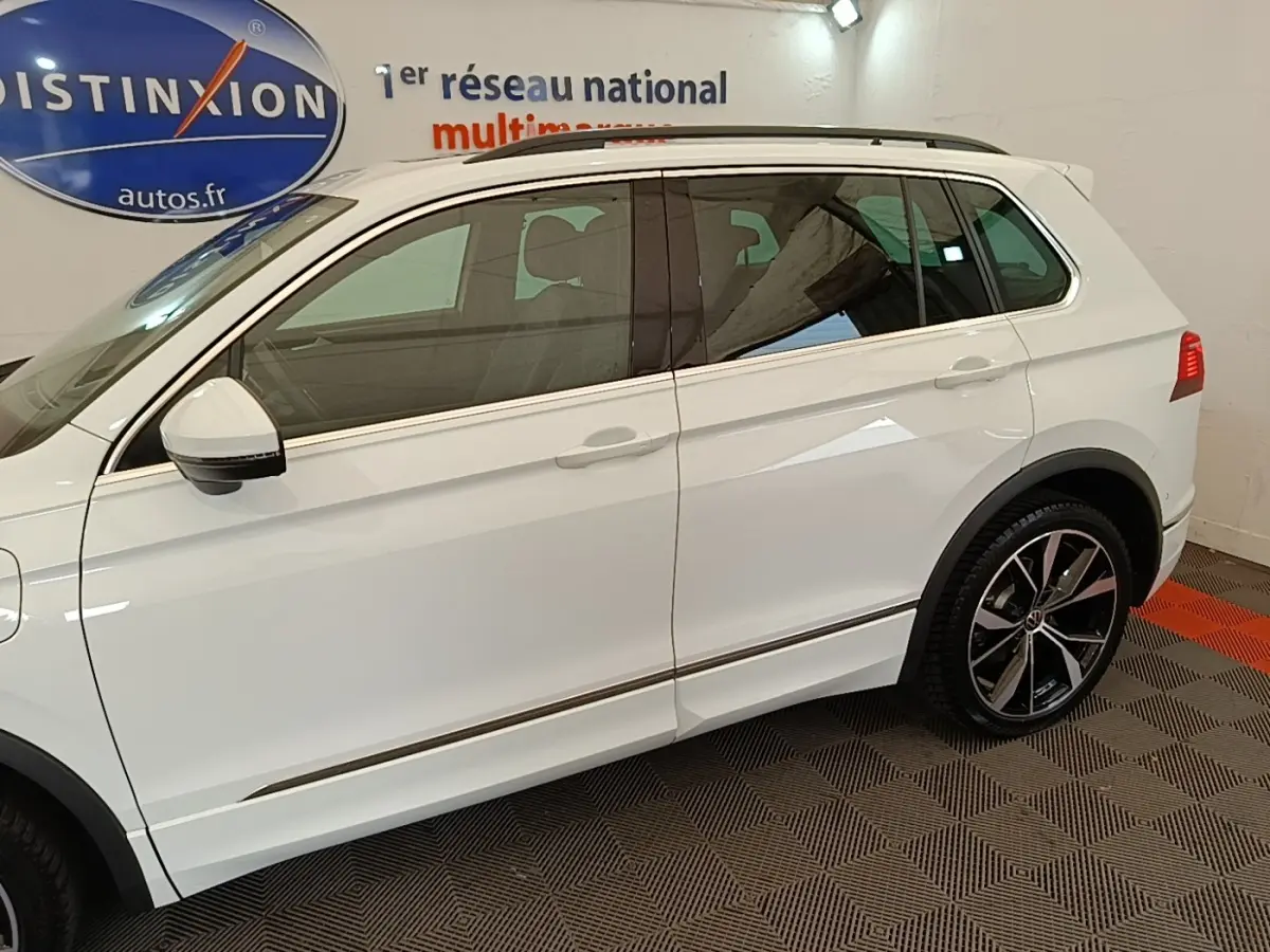 Profil côté gauche d’un Volkswagen Tiguan blanc 2023 avec jantes alliage noires et rétroviseurs électriques.