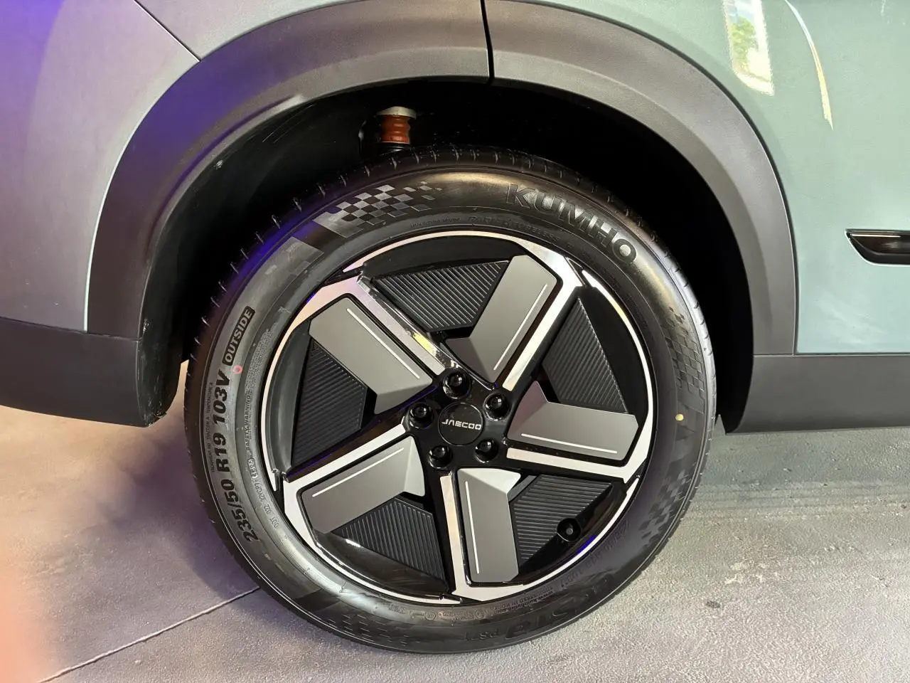 Gros plan sur la roue avant gauche du JAECOO J7 gris olive, mettant en valeur la jante alliage 19 pouces au design moderne.