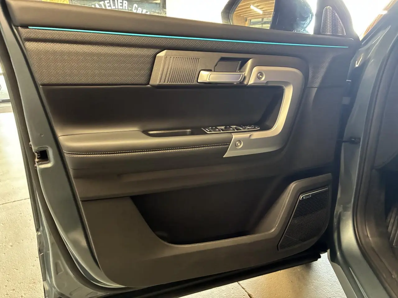 Vue intérieure côté conducteur de la porte du JAECOO J7 gris olive, avec habillage noir et haut-parleur Sony intégré.