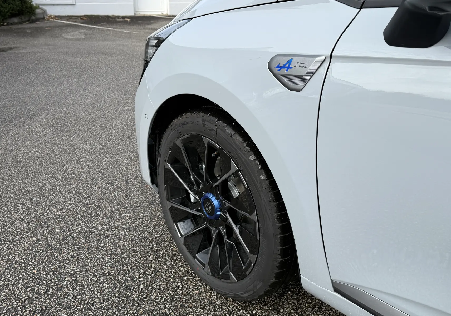 Gros plan sur la roue avant gauche et l'aile gris rafale d'une Renault Clio V Esprit Alpine 2025 avec logo bleu distinctif.