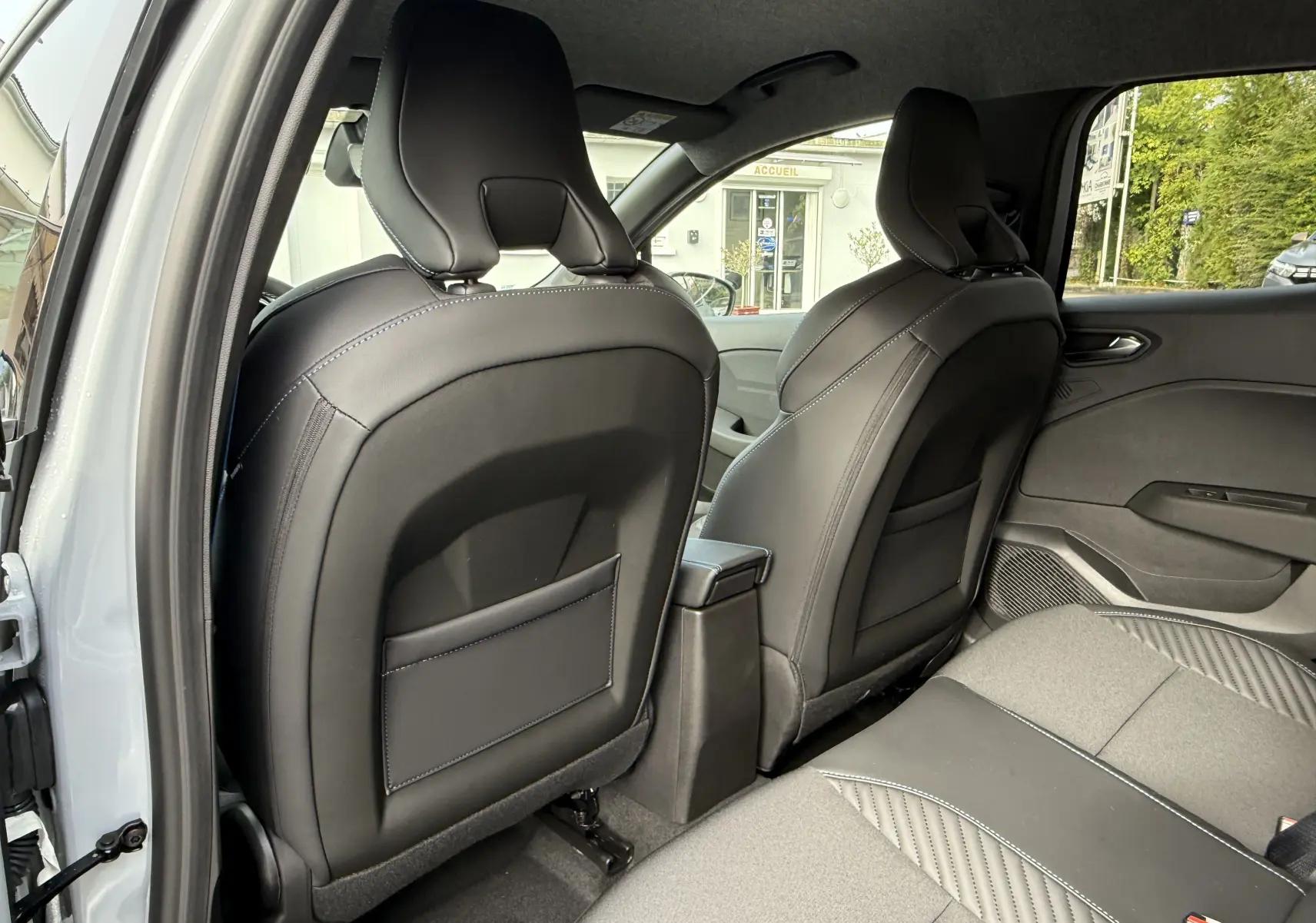 Vue arrière intérieure montrant les sièges avant en cuir noir et la banquette arrière grise de la Renault Clio V Gris Rafale 2025.