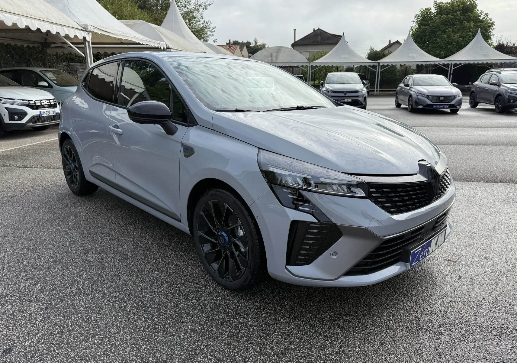 Renault Clio V gris Rafale vue 3/4 avant droit, avec jantes noires et calandre moderne en concession extérieure.