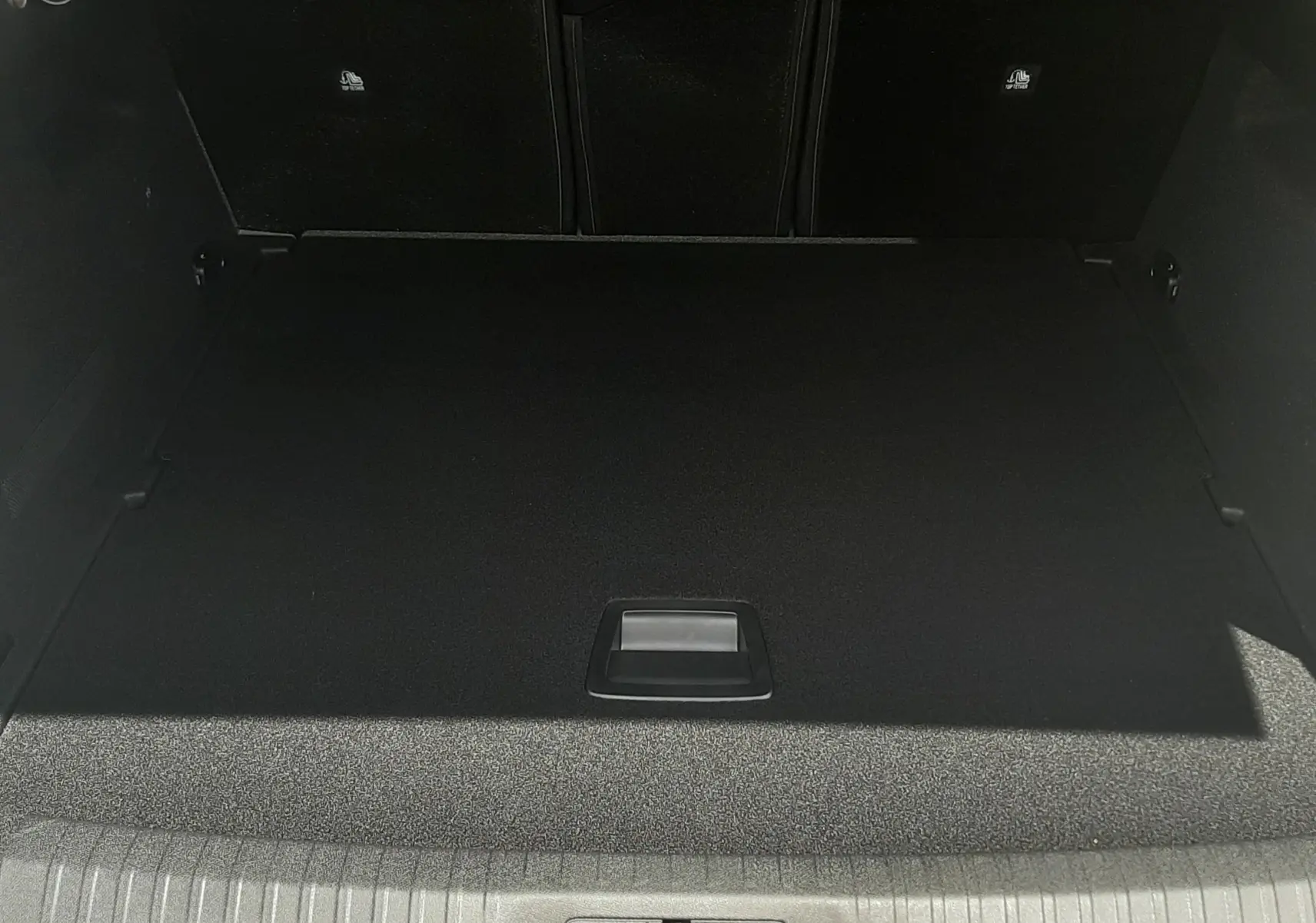Coffre ouvert vu de face du Peugeot 3008 1.2 Hybrid 145ch GT bleu Obsession, montrant le plancher plat et le rangement sous le tapis.
