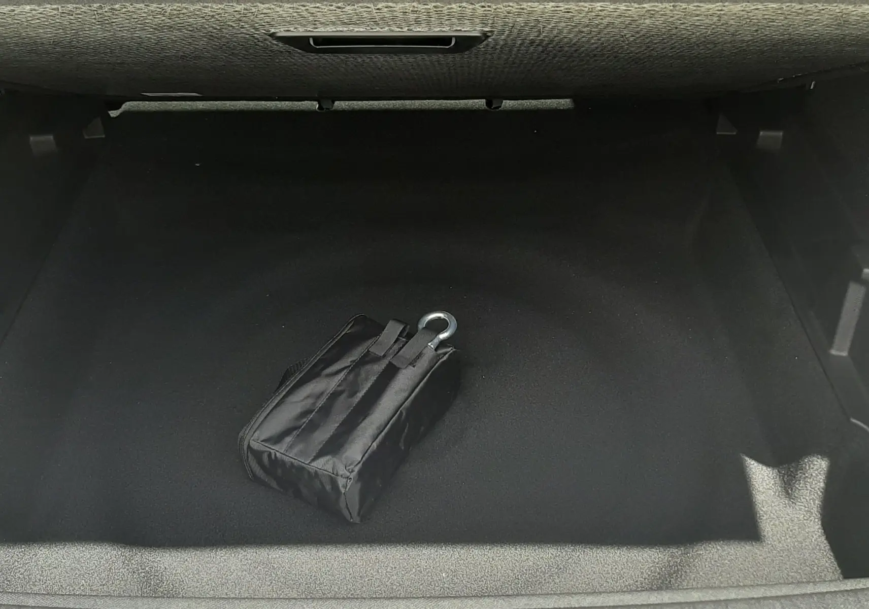 Vue plongeante sur le coffre vide d’un Peugeot 3008 1.2 Hybrid 145ch GT 2026, avec un kit de secours noir visible.