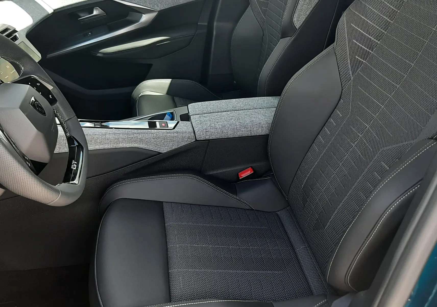 Vue intérieure côté conducteur du Peugeot 3008 1.2 Hybrid 145ch GT 2026 avec sièges tissu et cuir noir, volant compact GT.