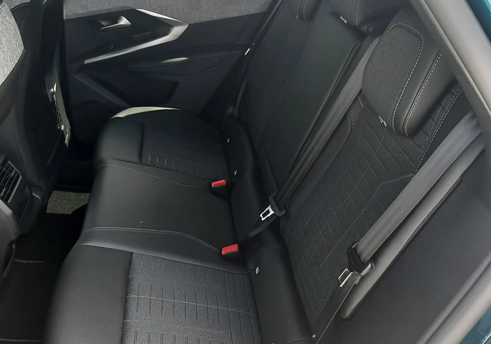 Vue intérieure côté droit des sièges arrière noirs du Peugeot 3008 1.2 Hybrid 145ch GT, avec porte ouverte bleu Obsession.