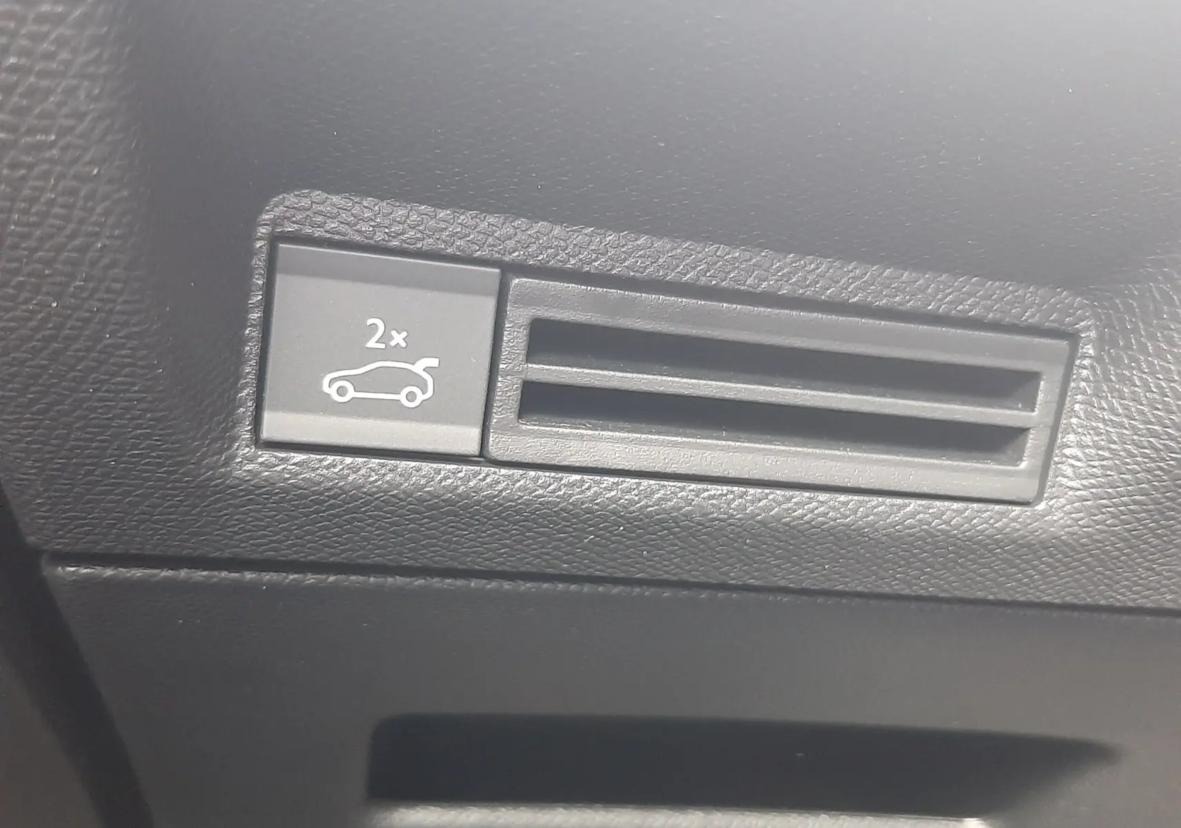 Gros plan sur le bouton d'ouverture du coffre dans l'habitacle noir du Peugeot 3008 1.2 Hybrid 145ch GT 2026.