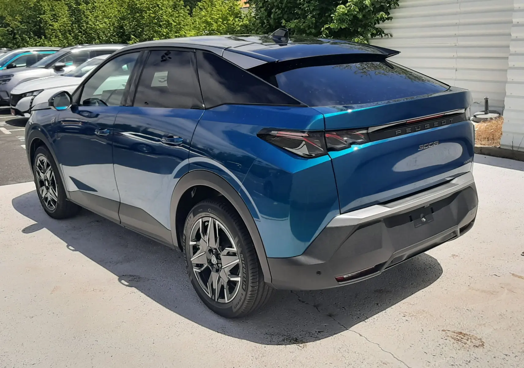 Peugeot 3008 1.2 Hybrid 145ch GT bleu obsession, vue 3/4 arrière droit, avec toit noir et jantes stylées.