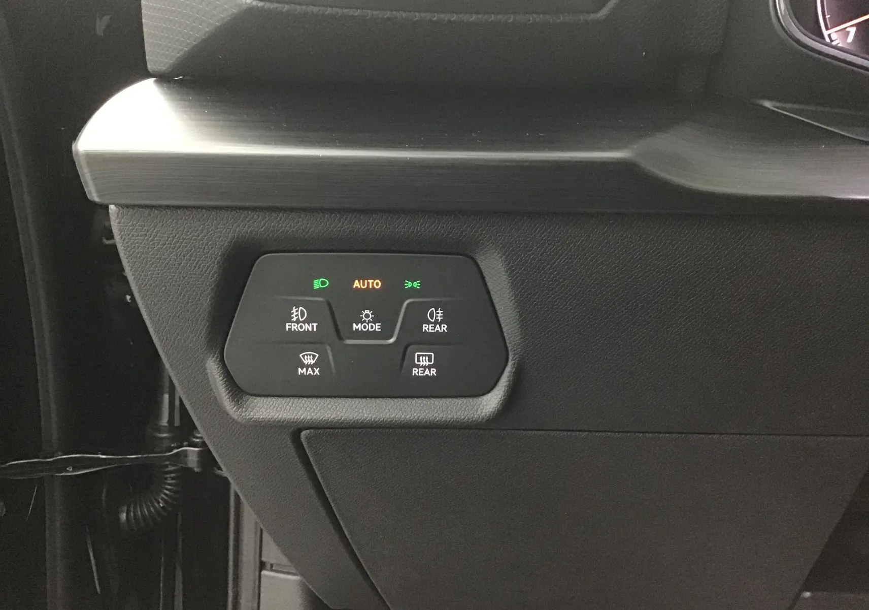 Gros plan sur les commandes d'éclairage et de désembuage côté gauche du tableau de bord noir du CUPRA Leon 2023.