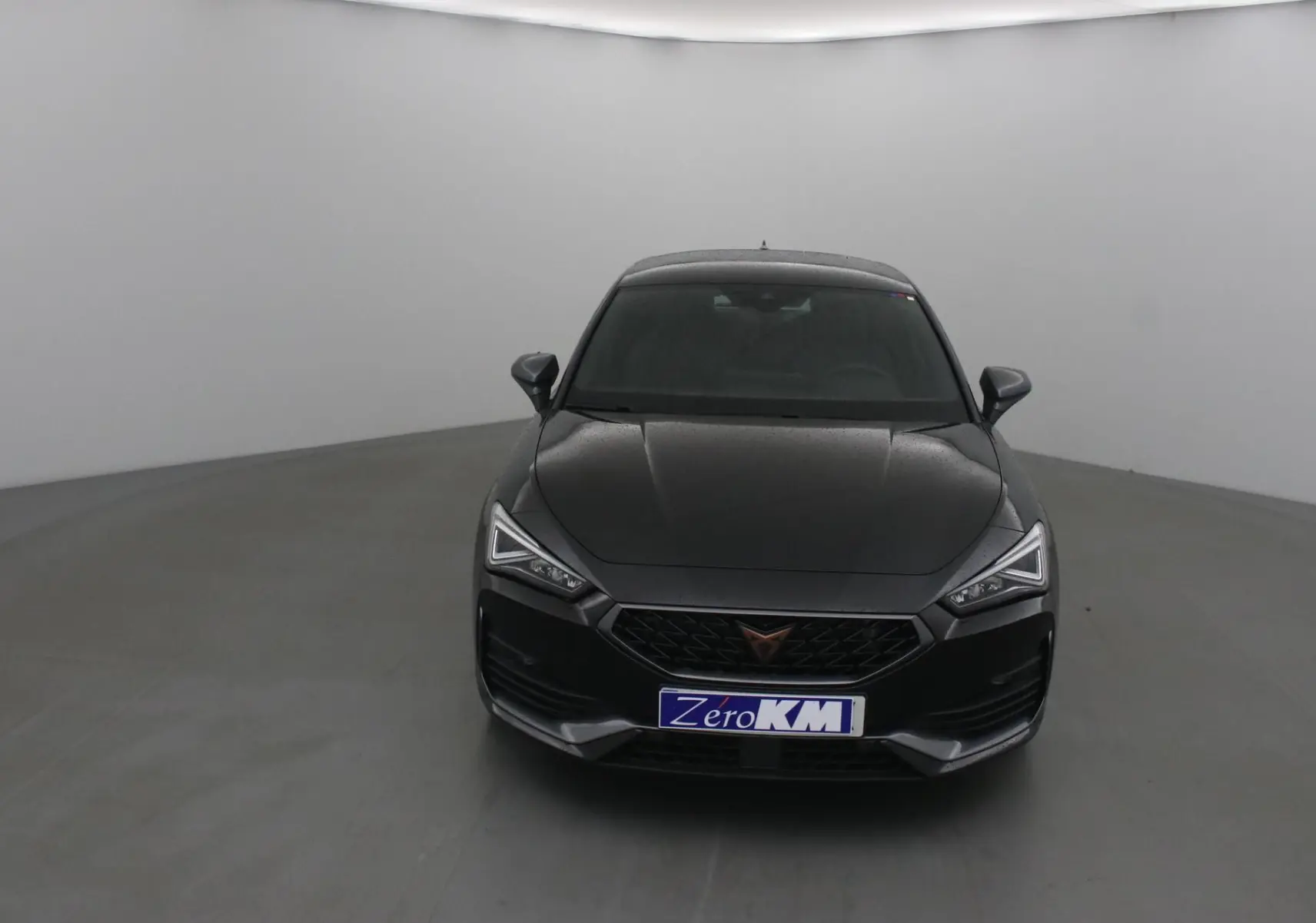Vue avant d'une CUPRA Leon noire 2023 avec calandre noire et phares LED anguleux dans un studio gris.
